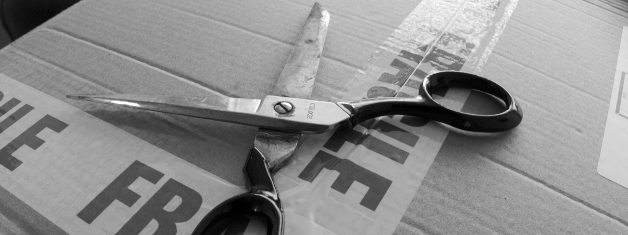 Scissors on top of a cardboard box with 'fragile' tape
