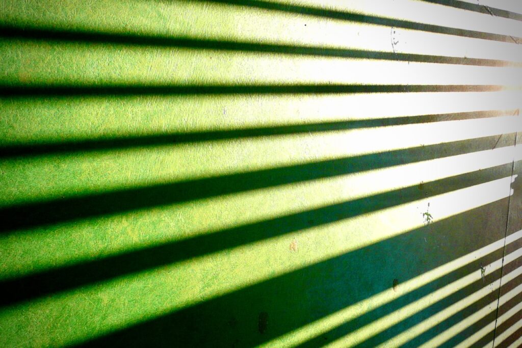 Sunlight through blinds on a green surface